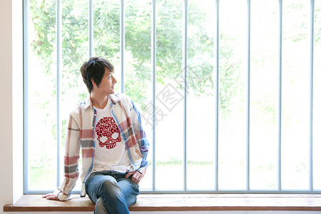 年轻男子坐在窗户前图片