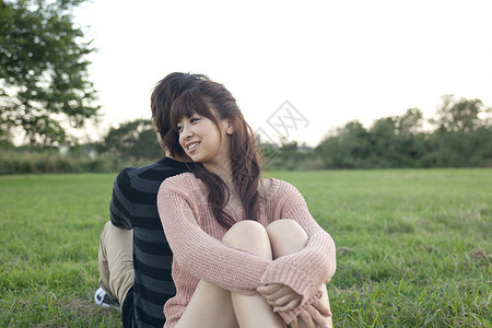 坐在草地上背靠背的情侣图片