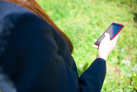 操作智能手机的学校女孩特写图片