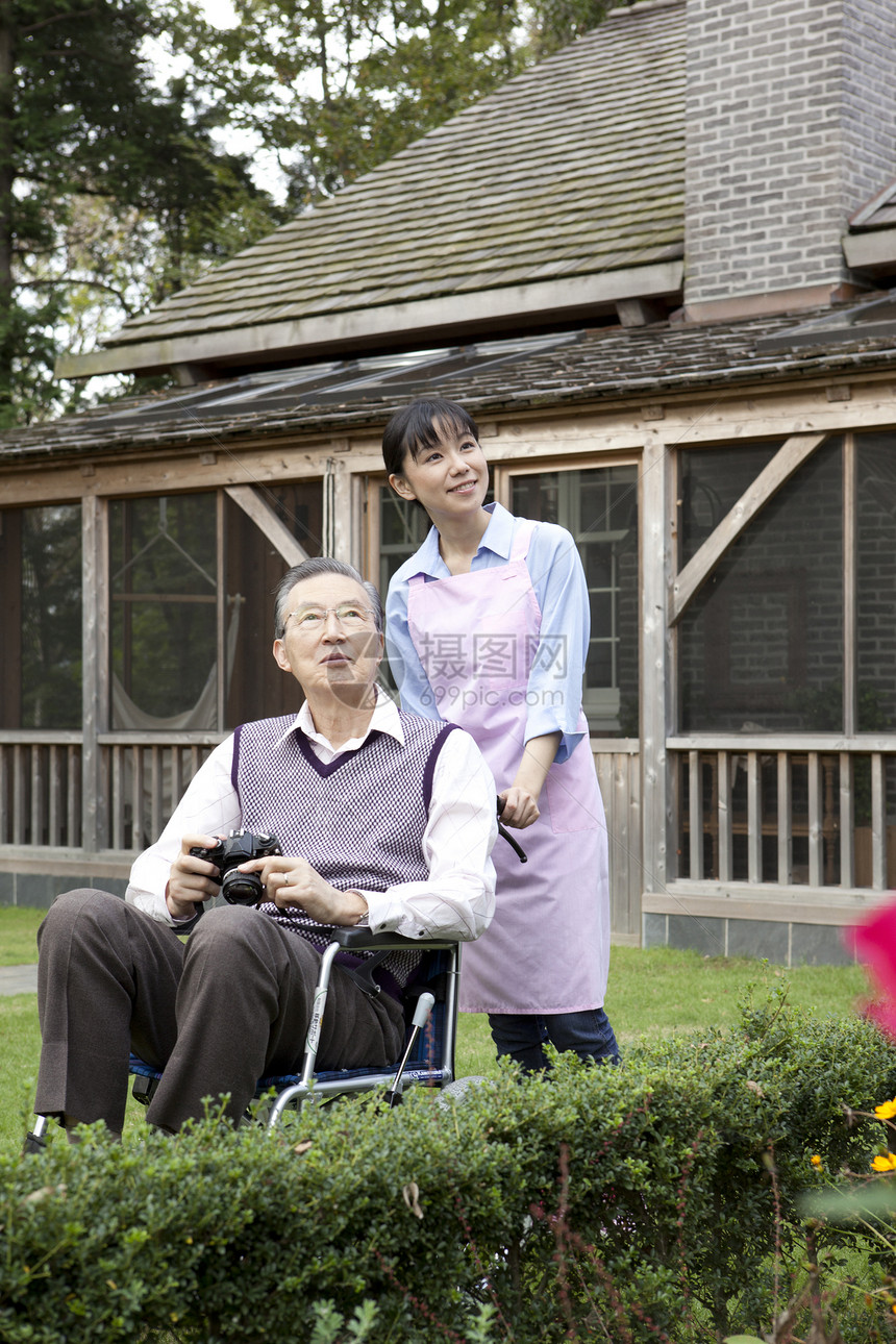 护工推轮椅上的爷爷到花园里散步图片