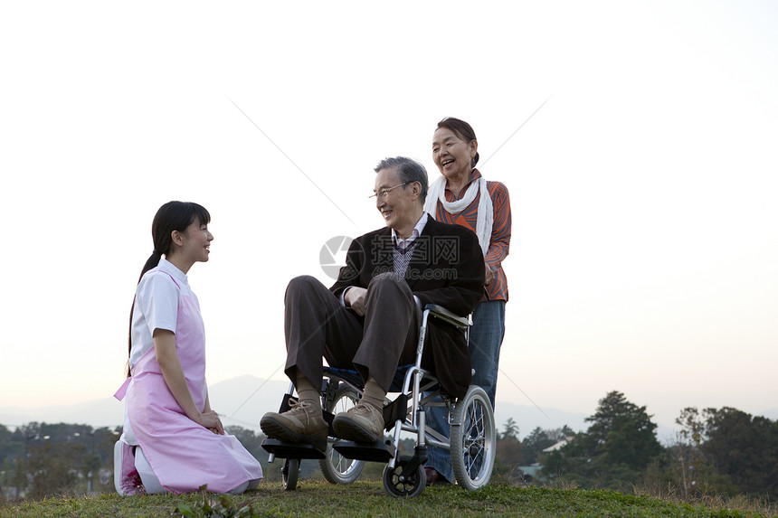 户外护工照顾推着轮椅上的老年人图片