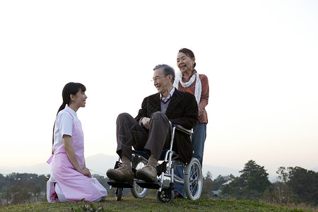户外护工照顾推着轮椅上的老年人图片