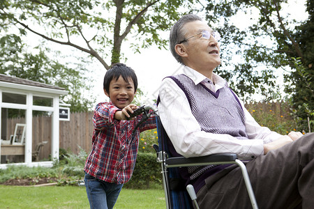 后院里孙子推着轮椅上的爷爷散步图片