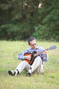 户外草地上中老年男性弹吉他图片