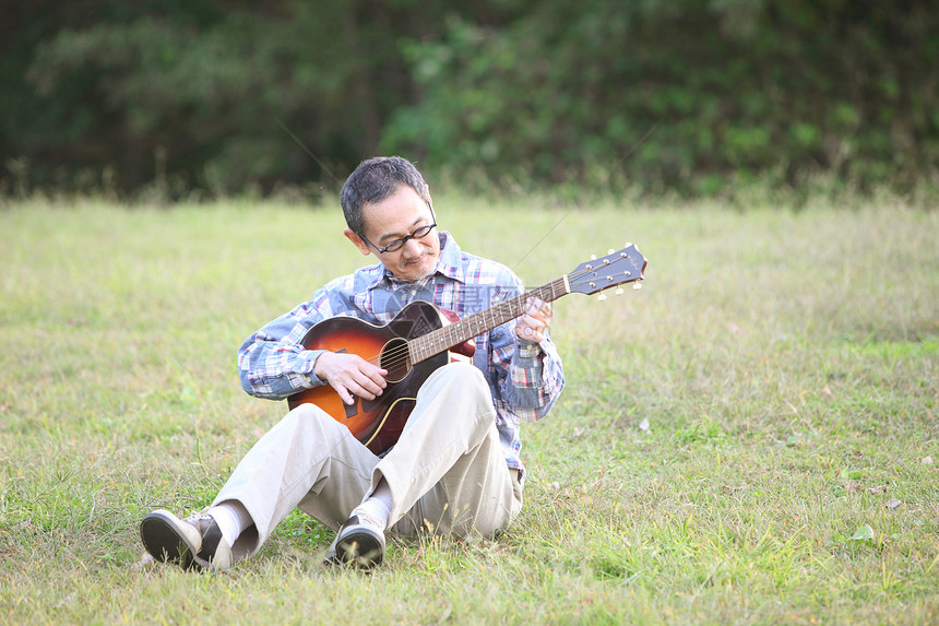 户外草地上中老年男性弹吉他图片