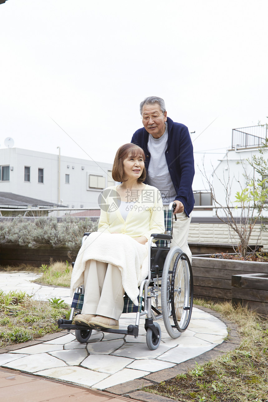 老年男性推着轮椅上的妻子图片