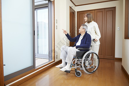 老年女性推着轮椅上的丈夫看窗外的风景图片