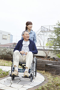 女人推着轮椅上的爷爷外出散步图片