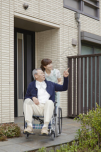 女性护工推着轮椅上的老人出门散步图片