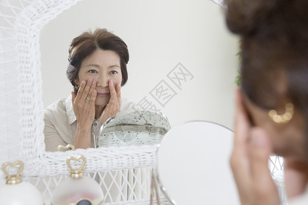 粉底液无暇美肌老年女性镜子前查看皱纹背景