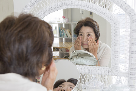 老年女性镜子前查看皱纹高清图片