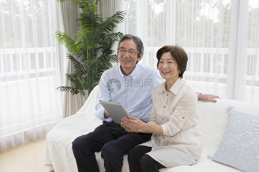 客厅沙发上的中老年夫妻看平板电脑图片