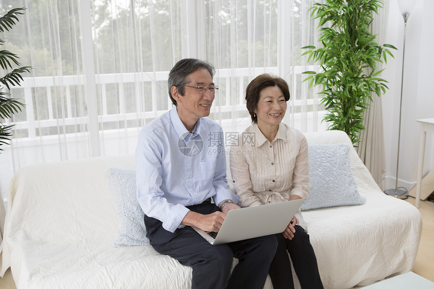 客厅沙发上的中老年夫妻看电脑图片