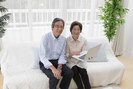 客厅沙发上的中老年夫妻使用电脑图片