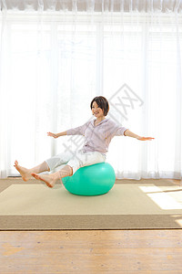 客厅里玩瑜伽球的妇女图片