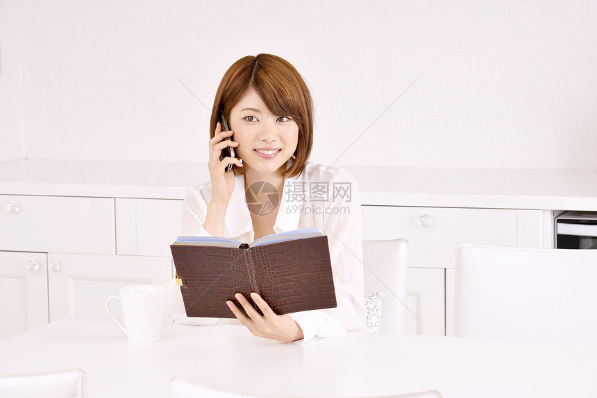 年轻女性看笔记本时打电话图片
