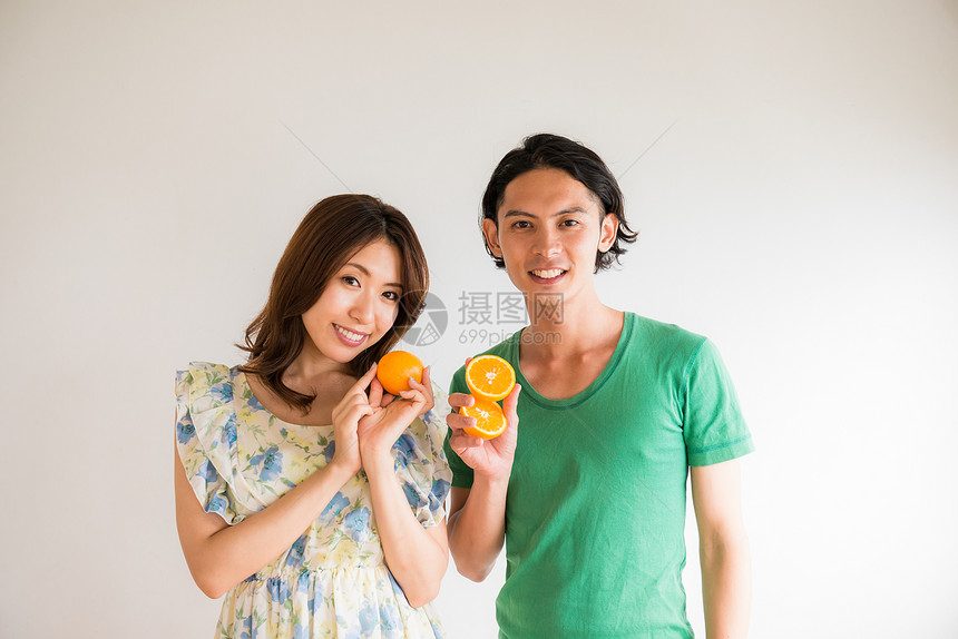 年轻情侣手拿橘子图片