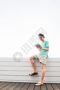 坐在护栏上看书的男子图片