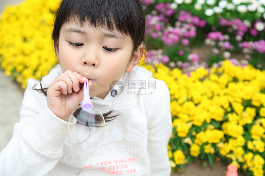 在花坛边吹泡泡的小女孩图片