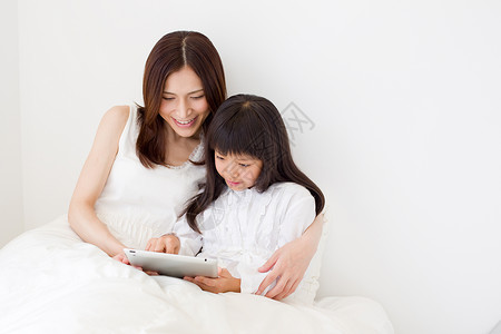 妈妈和孩子在床上看平板电脑图片