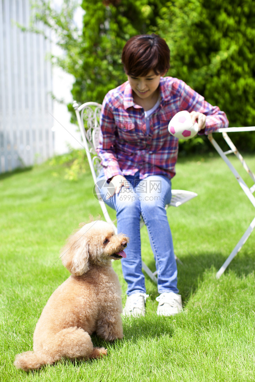 年轻女性带着宠物狗在花园玩耍图片