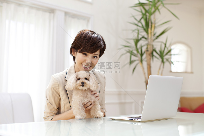 女性抱着狗狗在工作图片