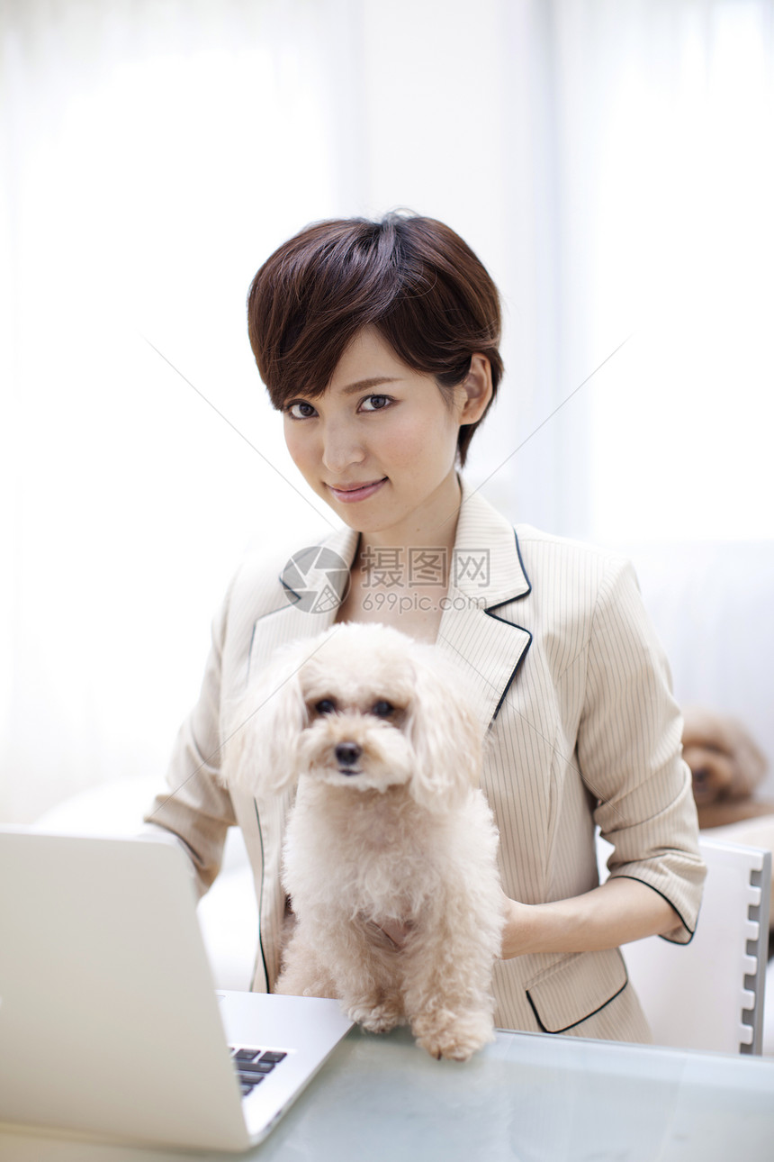 电脑前抱着贵宾犬办公的女主人图片