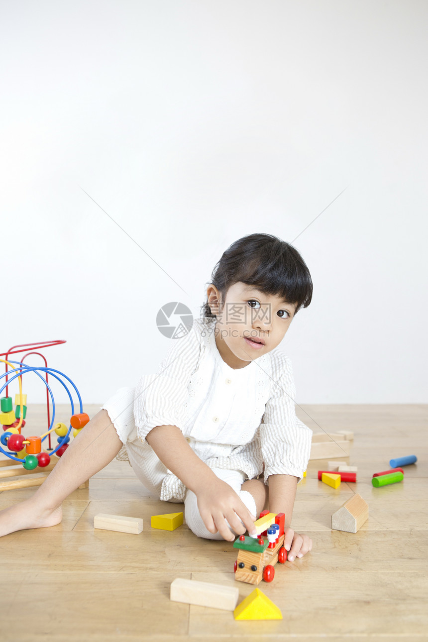 坐在地上玩玩玩具的小女孩图片