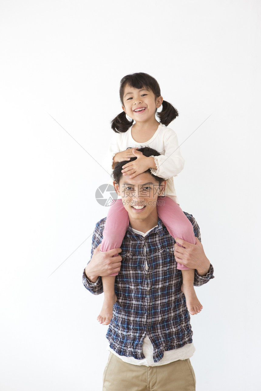 小女孩骑在父亲肩膀上玩耍图片