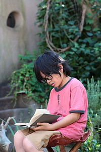 户外凳子上看书的男孩图片