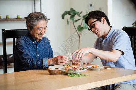 年轻男士给长辈斟酒高清图片