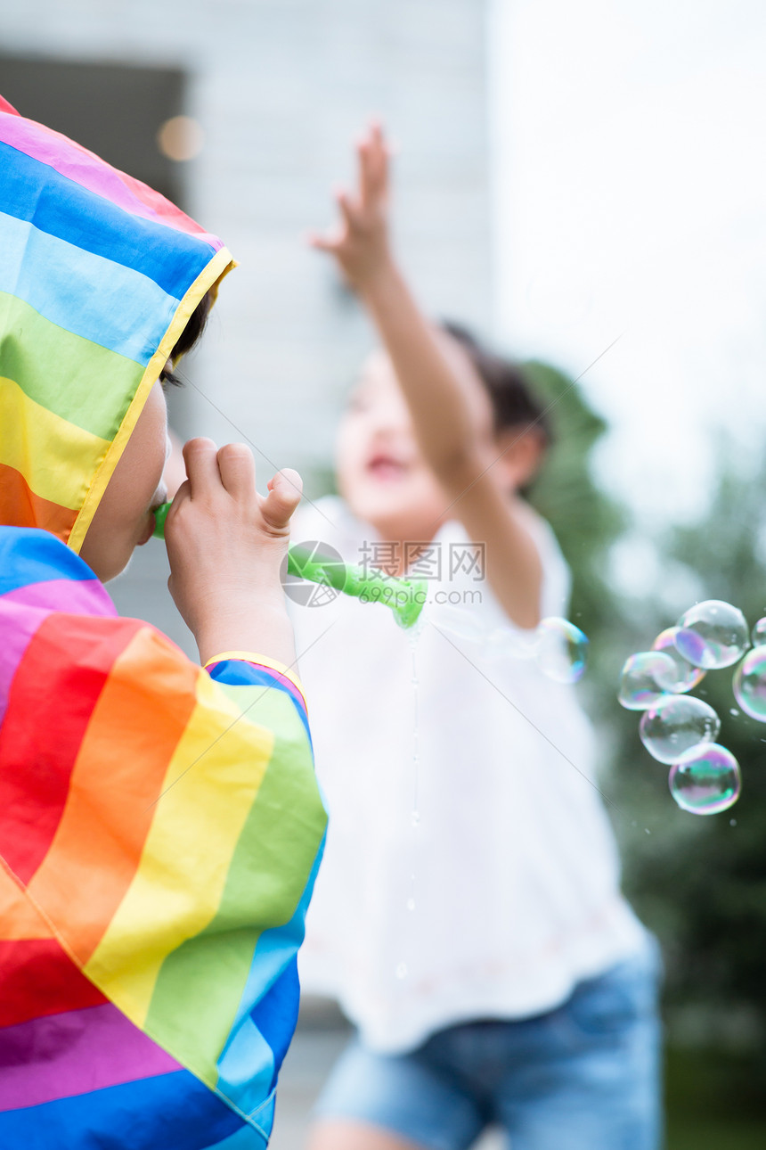 穿彩色雨衣的小男孩吹泡泡图片