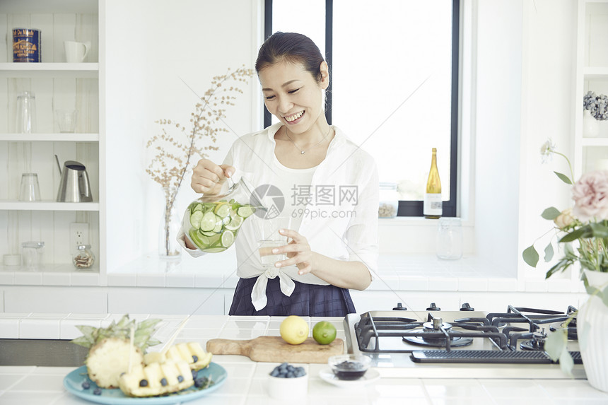 漂亮主妇在明亮的厨房里制作饮品图片