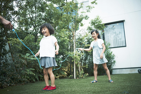 小女孩跳绳花园里玩耍的小女孩们背景