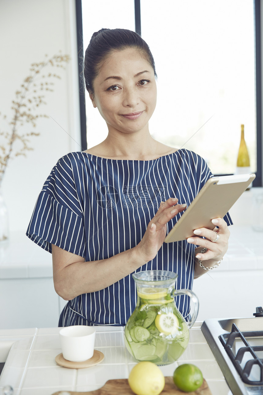 一名妇女在一个明亮的厨房里手拿平板电脑图片