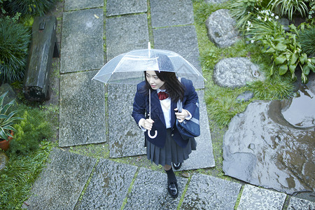 雨天撑伞上学的女高中生背景图片