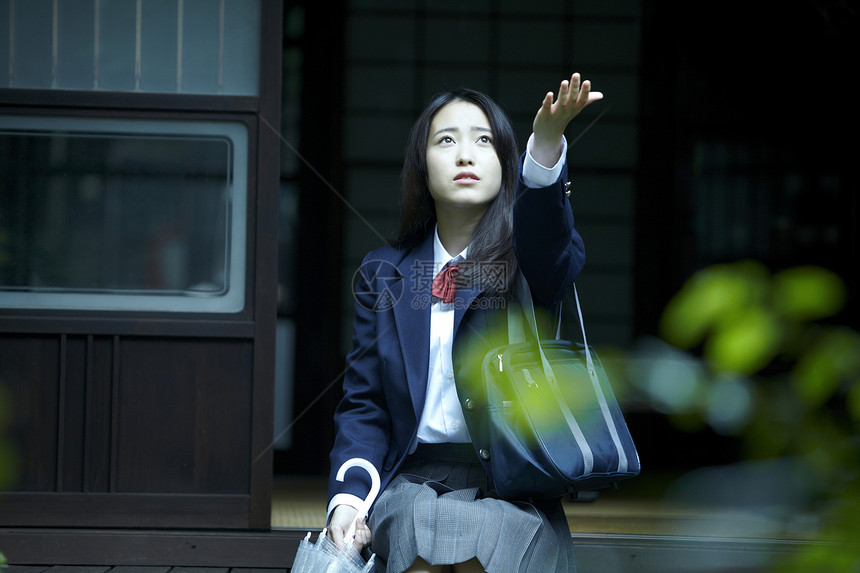 雨天从房屋外伸出手的女孩图片