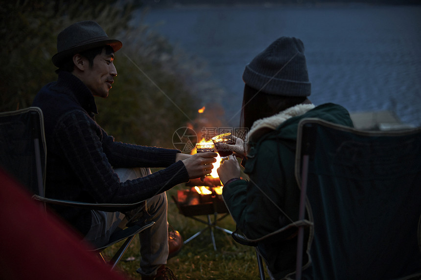 一对夫妇在篝火旁碰杯图片