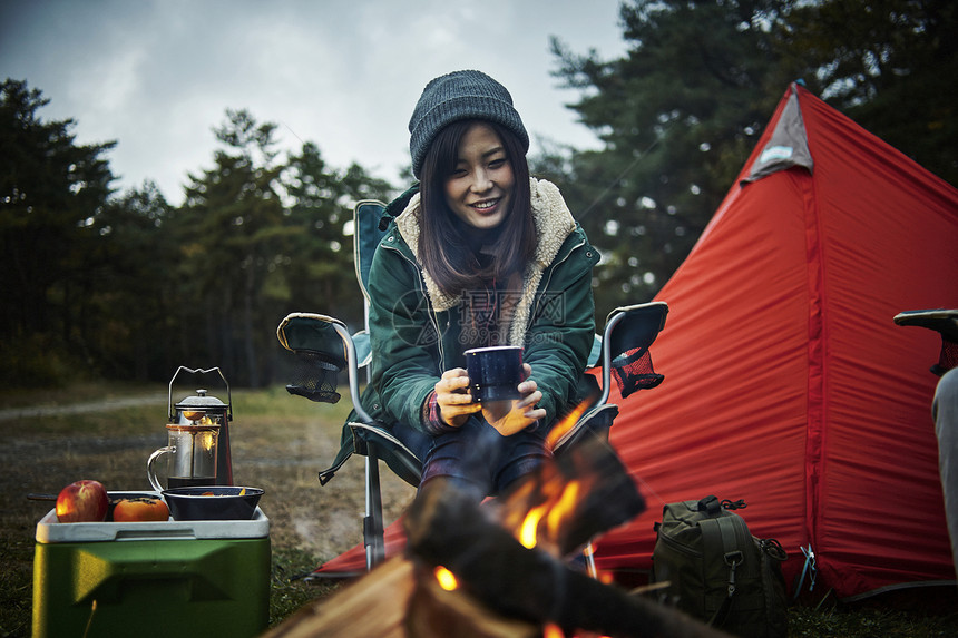 营火边喝咖啡的女性图片