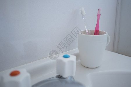 盥洗室卫生间里的牙刷和杯子图片