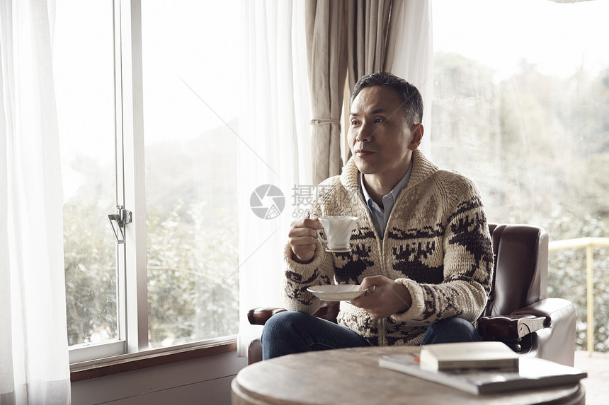 中年男子坐在窗边喝咖啡图片