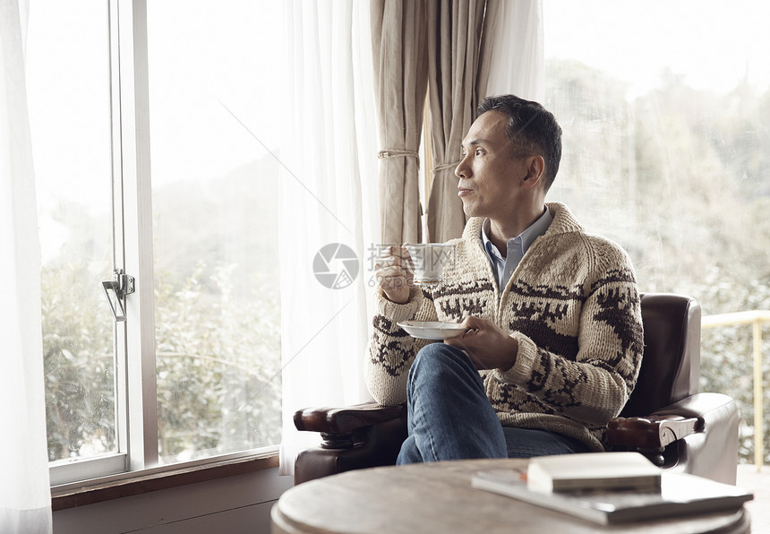 扮男子坐在窗边喝咖啡图片