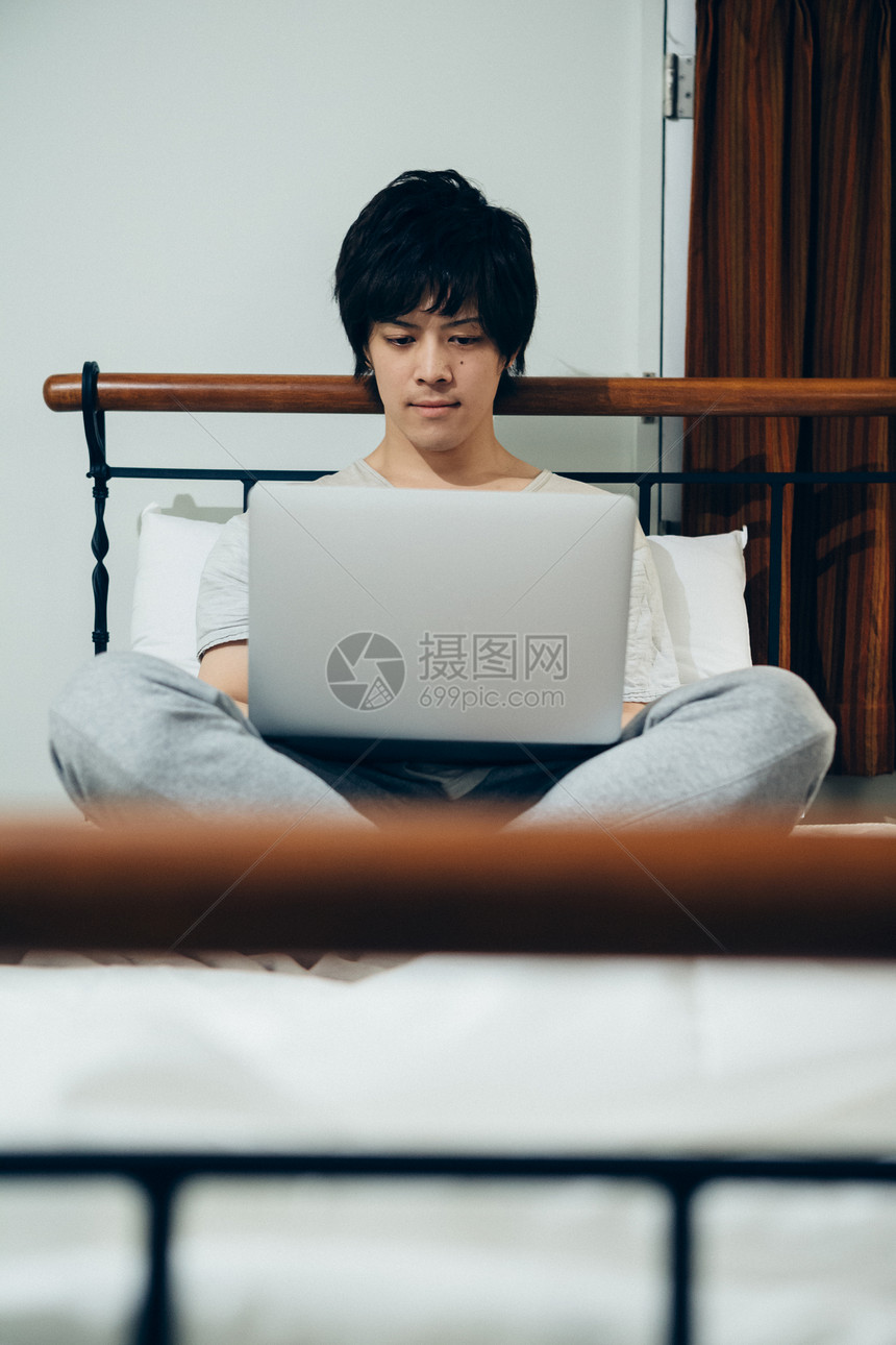 一个男人在床上看电脑图片