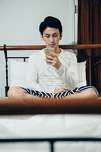 在床上玩智能手机的男生图片