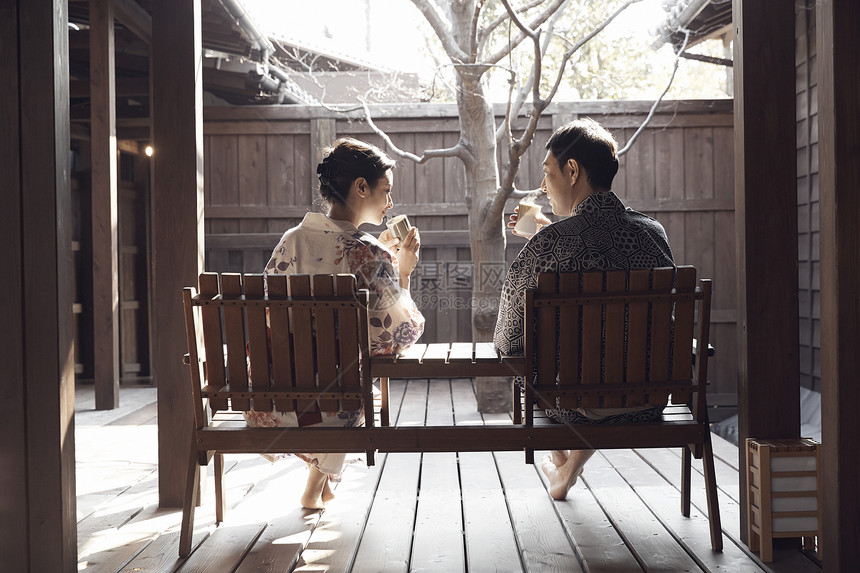 在温泉酒店的一对夫妇坐在木椅上喝茶休息图片
