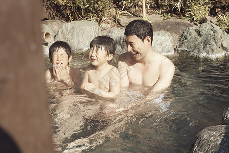 父母和孩子享受户外温泉浴池图片