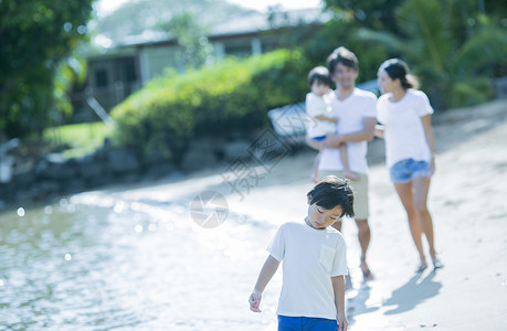 国外父母素材父母和孩子沿着海滩散步背景