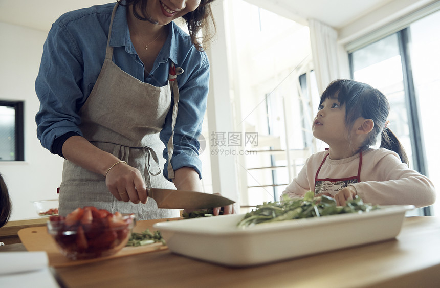 小女孩看着正在做饭的母亲图片