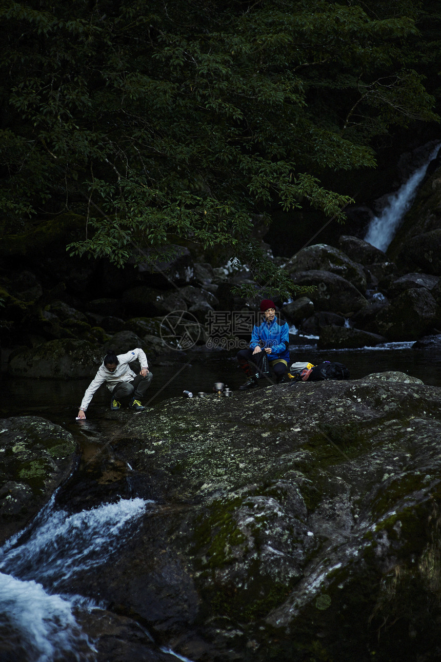山林中旅行的两个男性在溪边休息图片