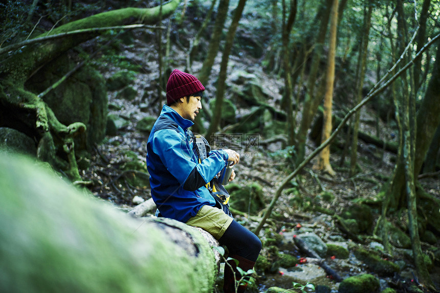 森林中冒险旅行的男背包客坐着休息图片